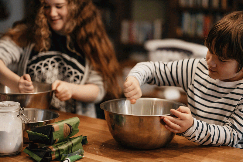 brother and sister at kitchen counter stirring metal bowls