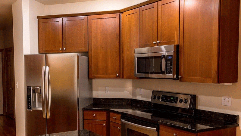 cropped shot of countertops and microwave suspended from cabinetry