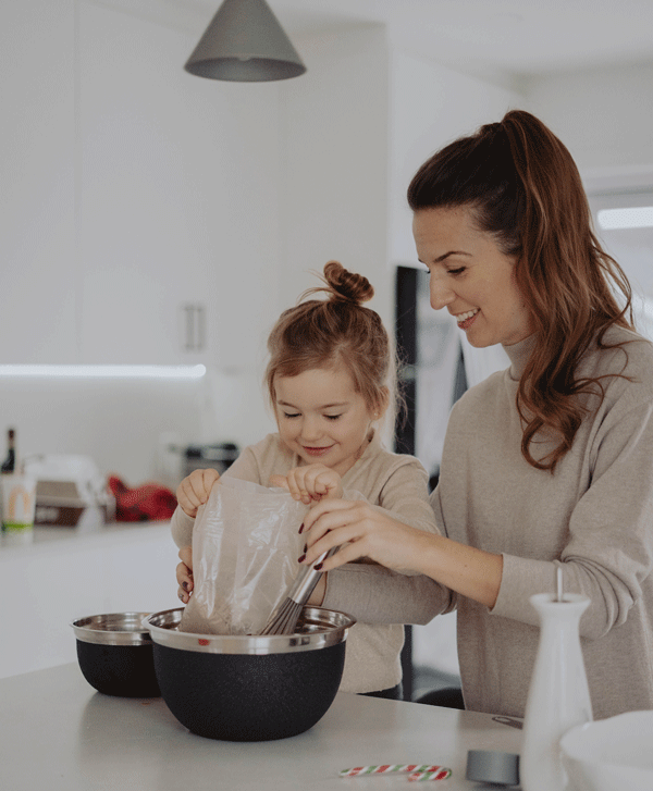 young daughter helping mother add bag of food to bowl